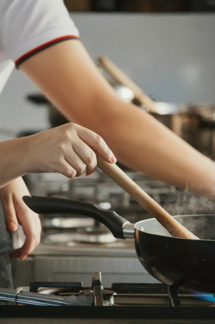 Deux personnes cuisinent ensemble dans une poêle pendant un cours à domicile