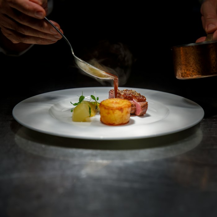 Plat raffiné dressé dans une assiette, résultat d'un cours de cuisine en visio